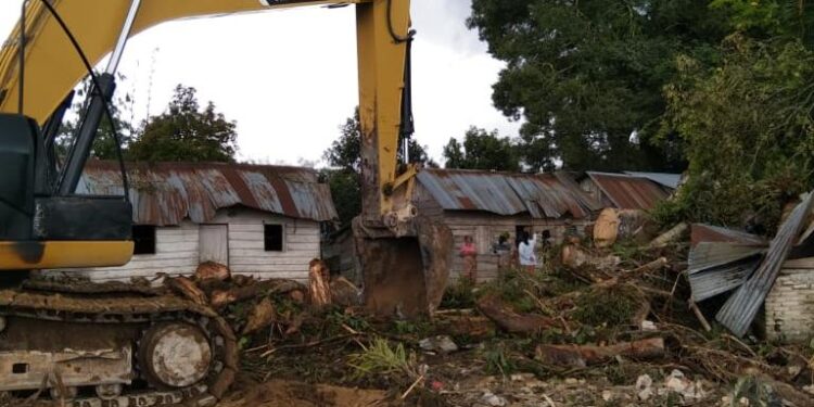 Teks foto : Alat Exvator Milik BPBD Humbahas Mengevakuasi Pohon Tumbang Yang Menimpa Rumah Warga.
