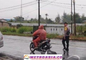 Diguyur Hujan, Polsek Raya Tetap Bertugas Atur Lalu Lintad di Simpang Sekolah