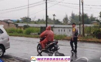 Diguyur Hujan, Polsek Raya Tetap Bertugas Atur Lalu Lintad di Simpang Sekolah